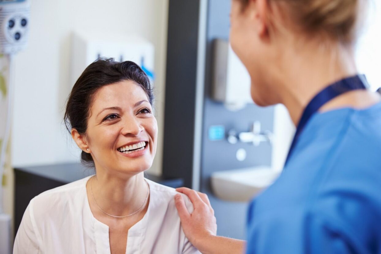 Smiling patient talking with a dental professional in a clinic.