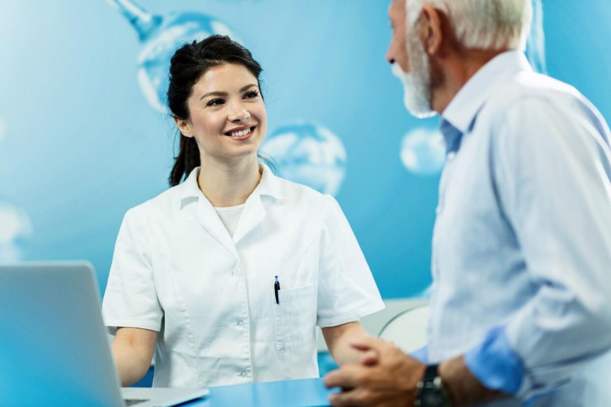 Dentist smiling and talking with an older patient at a clinic